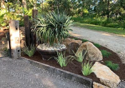 Garden bed using steel planter, recycled railway timbersk and basalt rocks